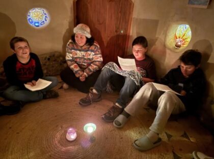 Teacher Sam gathers with UUCE youth, Silas, Simon, and Toby in the Cob House during the Coming of Age Sleepover. 